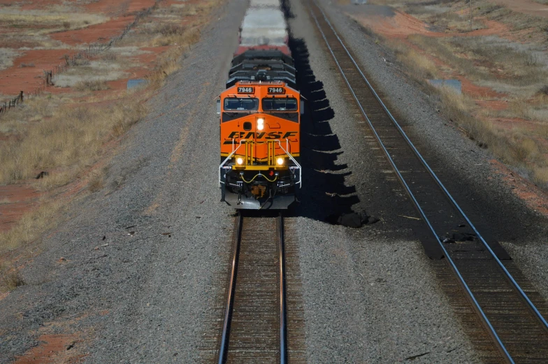 a large long train on a steel track, by Jeffrey Smith, pexels contest winner, photorealism, orange and black, new mexico, high - angle view, high quality picture