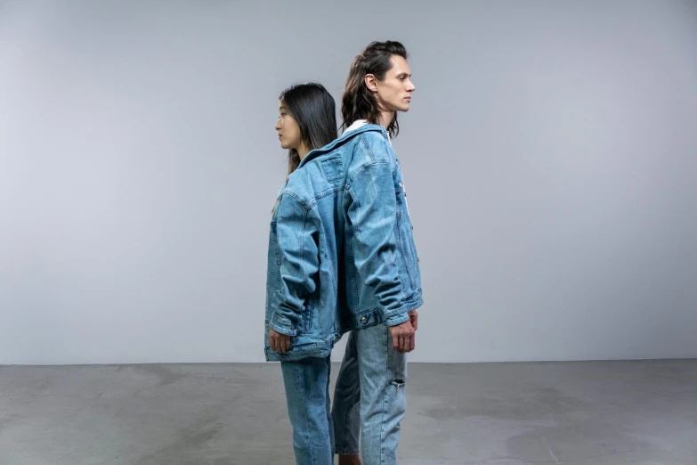 a woman in blue jeans and a girl with long hair are standing back to back in an empty room