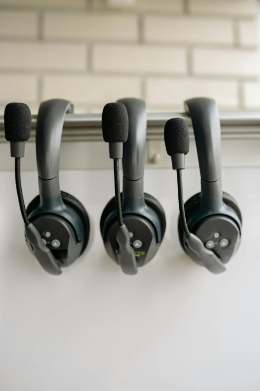 a row of headphones hanging on a wall, in an call centre office, david myers, panel, no - text no - logo