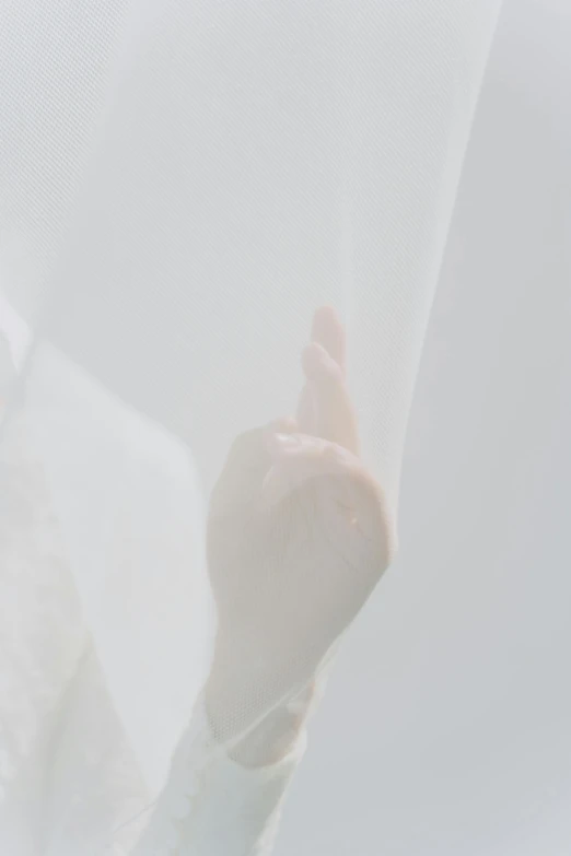 a person sticking their hand up behind a white curtain