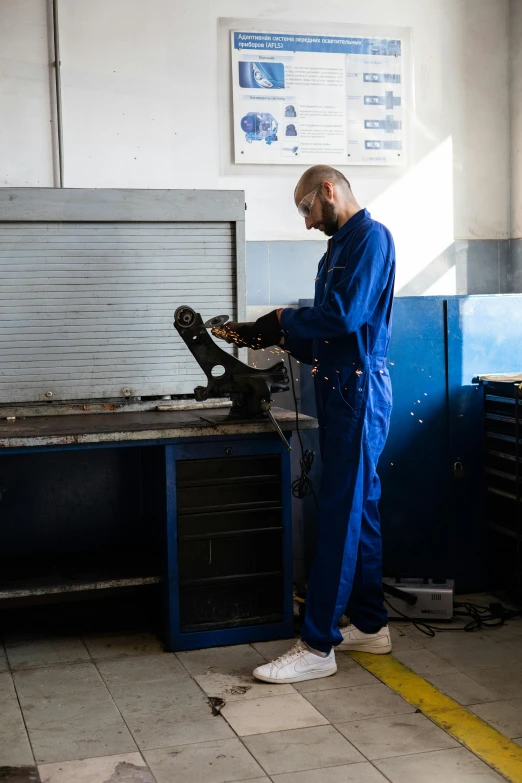 a man working on a car in a garage, inspired by Afewerk Tekle, blue, made from mechanical parts, thumbnail, - 8