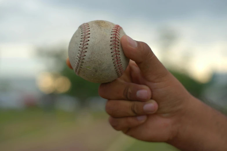 a baseball ball in a hand outside