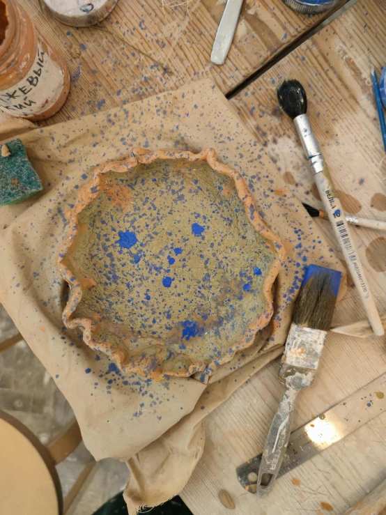 a table topped with a pie sitting on top of a wooden table, inspired by Giovanni Giacometti, process art, blue paint splash, clay material, ochre, starry