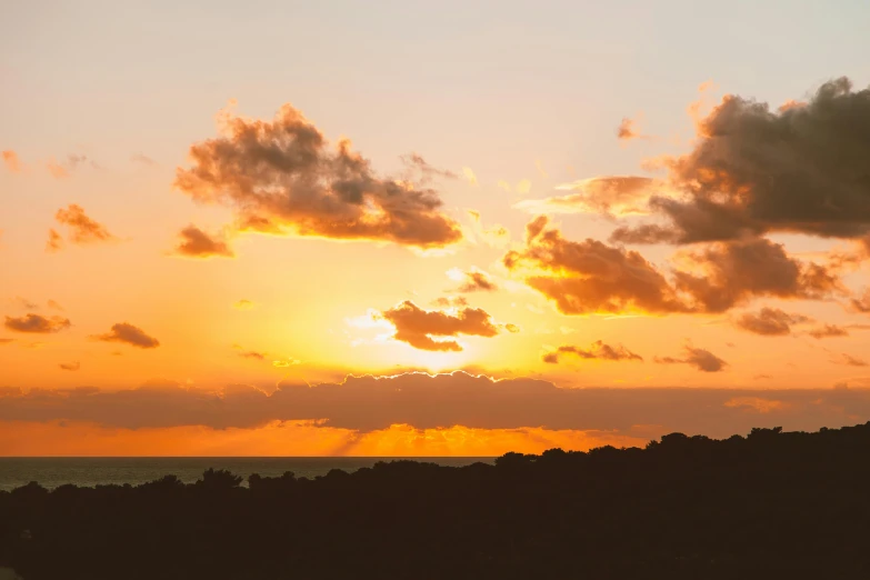 a man flying a kite on top of a lush green field, by Daniel Lieske, pexels contest winner, sunset panorama, seaview, orange clouds, silhouette over sunset