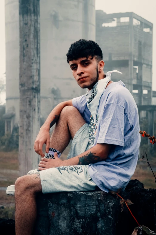 a young man sitting on top of a rock, an album cover, inspired by Byron Galvez, trending on pexels, hyperrealism, bad bunny, jean deville, wears shorts, shabab alizadeh