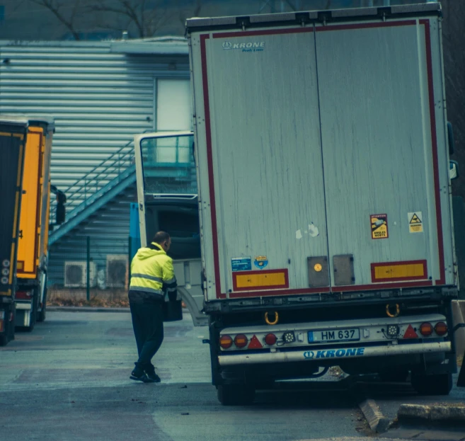 a man standing next to a truck in a parking lot, by Andries Stock, pexels contest winner, renaissance, security robots delivery, avatar image, half turned around