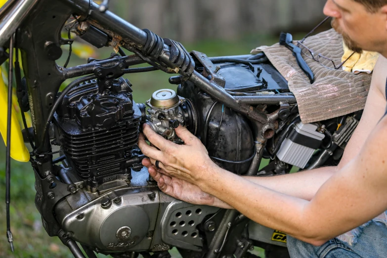 a man working on a motorcycle in the grass, by Jason Benjamin, unsplash, photorealism, leaking pistons, scrambler, restomod, woman