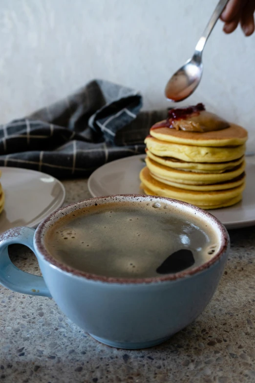 a cup of coffee and some pancakes on the table