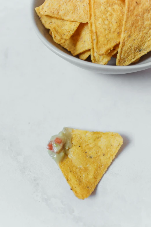 a bowl filled with tortilla chips next to a white plate with a serving