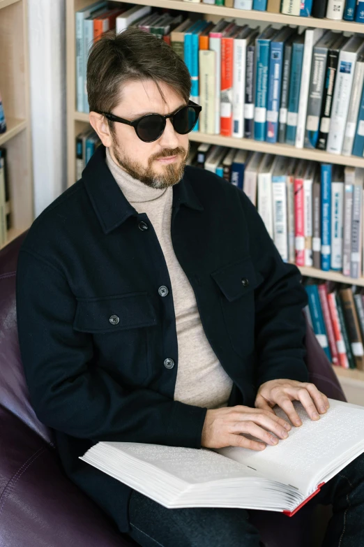 a man sitting in a chair reading a book, inspired by Thomas Mann Baynes, trending on reddit, renaissance, wearing a turtleneck and jacket, wearing shades, charlie cox, sitting at desk at keyboard