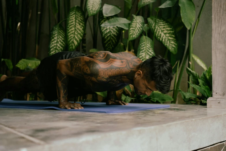 a man is doing a push up on a yoga mat, a tattoo, pexels contest winner, covered in plants, malaysian, profile image, brown body