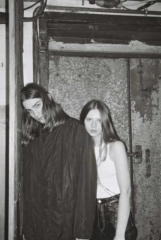 a couple of people standing next to each other, a black and white photo, tumblr, international gothic, young with long hair, in style of petra collins, press photo, concert