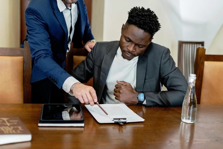 a couple of men that are sitting at a table, pexels contest winner, signing a bill, ( ( dark skin ) ), professional comercial vibe, lawyer clothing