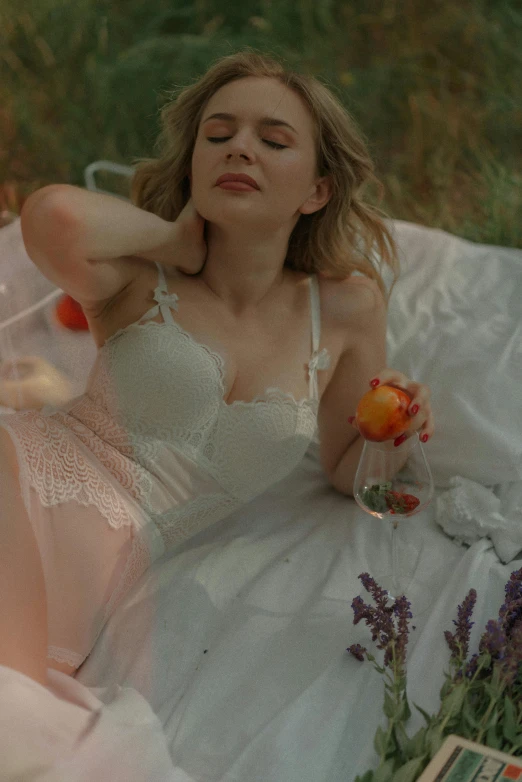 a woman laying on a bed with a glass of wine, inspired by Elsa Bleda, unsplash, renaissance, wearing white dress, wearing bra, in the garden, gif