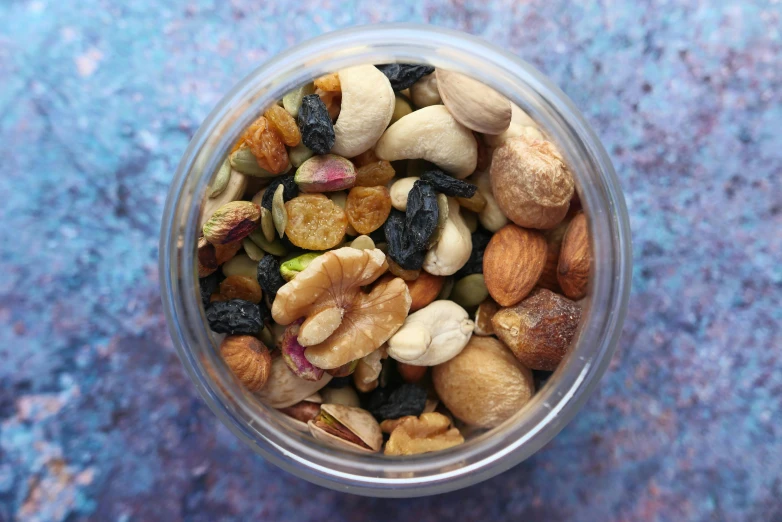 a jar filled with nuts and raisins on a table, by Julia Pishtar, trending on pexels, high angle close up shot, navy, multicoloured, round