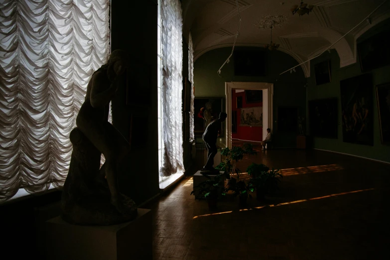 a statue sitting on top of a wooden floor next to a window, a statue, mannerism, museum lighting, shadowy figures, anna podedworna, in an art gallery]