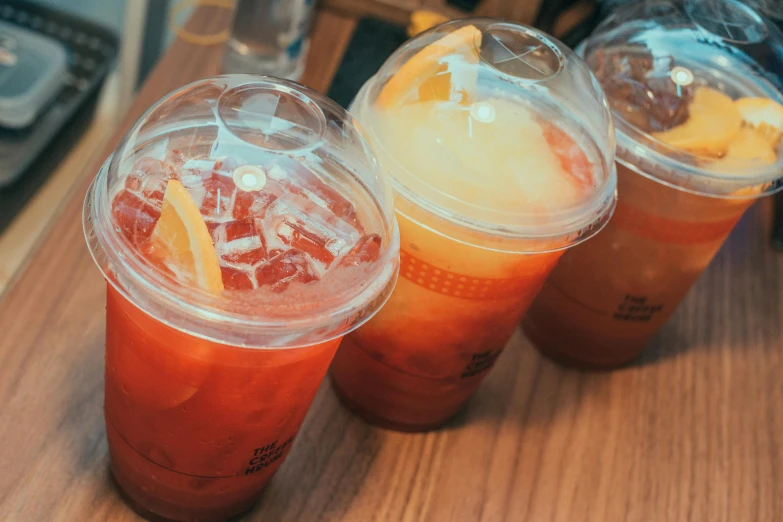 three drinks sitting on top of a wooden table, pexels, orange halo, drinking boba tea, 2 0 0 0's photo, jelly