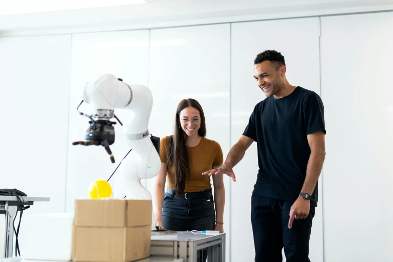 a man and a woman standing in front of a robot, pexels contest winner, teaching, cardboard, avatar image, people at work