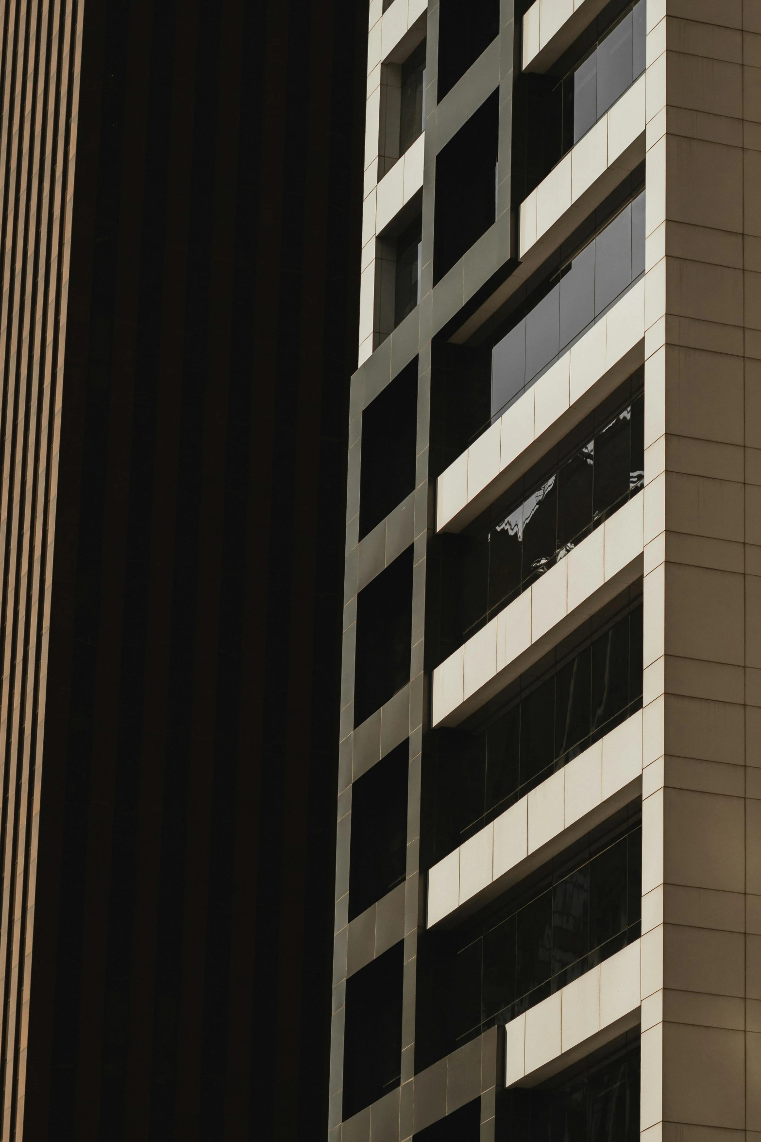 a clock mounted to the side of a tall building, a photo, inspired by Ned M. Seidler, unsplash, modernism, strong contrasting shadows, beige and dark atmosphere, three towers, buildings photorealism