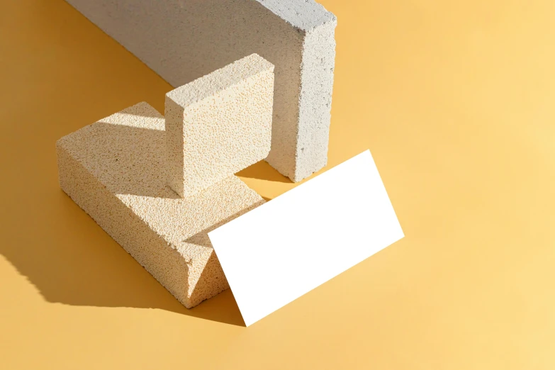 a white business card sitting on top of a pile of bricks, inspired by Bauhaus, trending on pexels, sand color, yellow charcoal, building blocks, background image