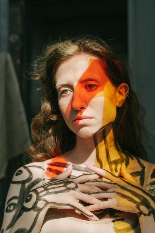 a woman with orange and yellow paint on her body, an album cover, inspired by Anna Füssli, pexels contest winner, portrait of sanna marin, lgbtq, center of picture, markings on her face