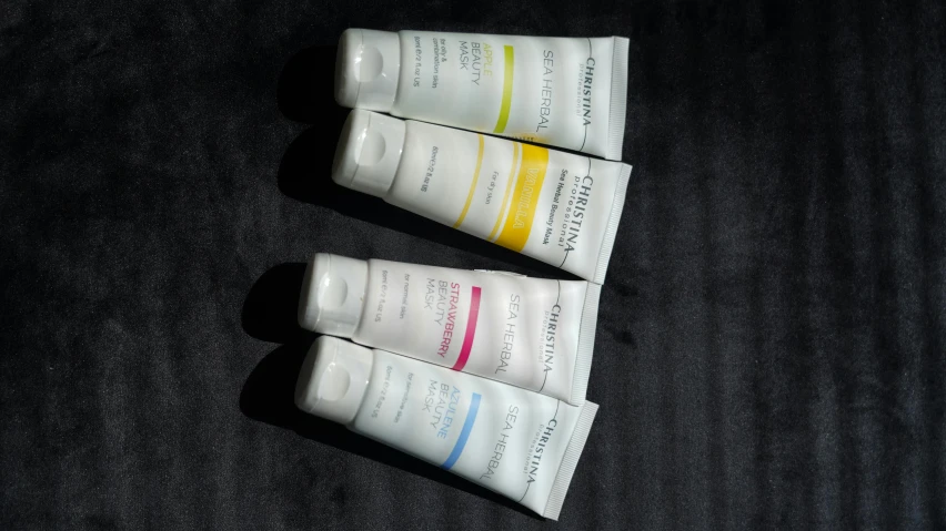 three tubes of toothpaste sitting on a black surface, inspired by Évariste Vital Luminais, plasticien, face mask, carrington, 4 colors, sky line