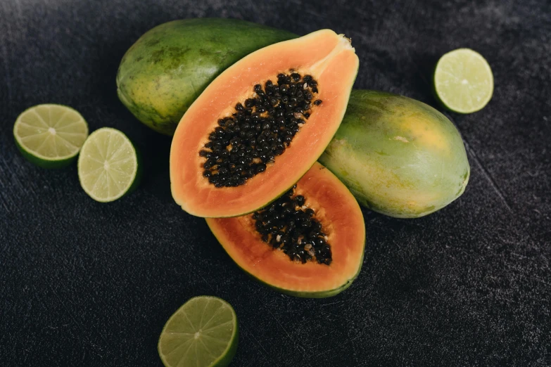 a couple of papanas sitting on top of a table, orange and black, pristine skin, lime, seeds