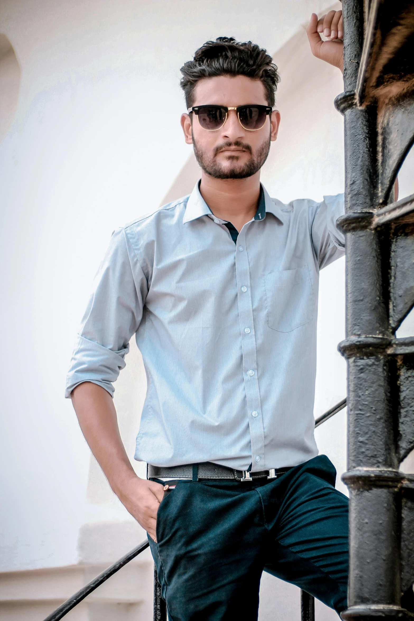 a young man in sunglasses posing on a stair case