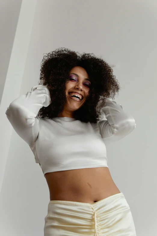 a woman in a white top and skirt posing for a picture, an album cover, inspired by Whitney Sherman, trending on pexels, laughing, afro futuristic, beautiful midriff, photoshoot for skincare brand