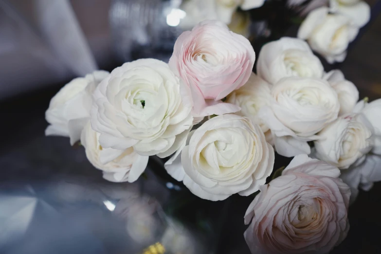 white roses sitting in a glass vase that's half open