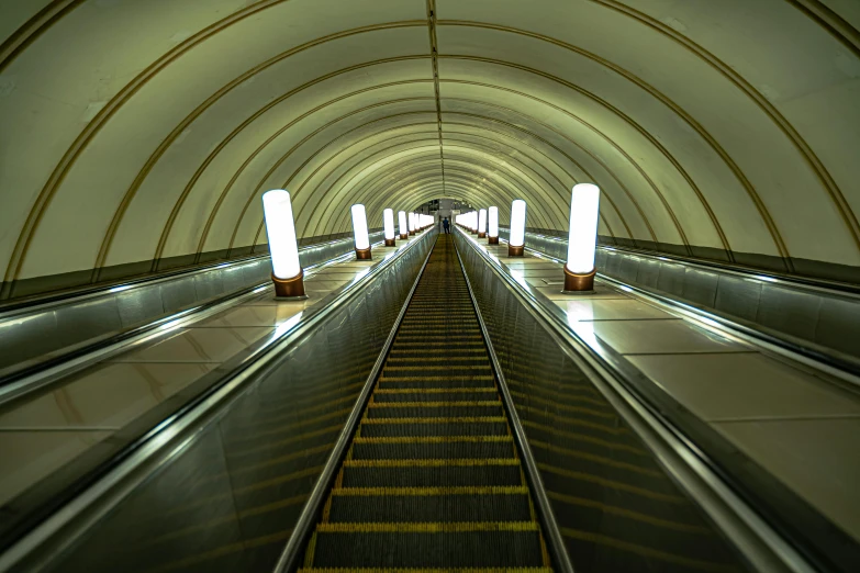 a very long metal moving escalator in a tunnel