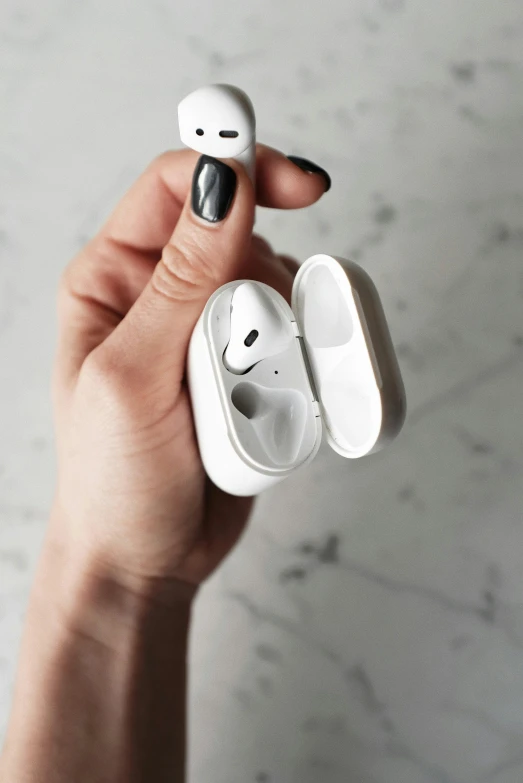 a person holding an airpods in their hand, by Julia Pishtar, trending on pexels, white ceramic shapes, top lid, case, close-up shot taken from behind