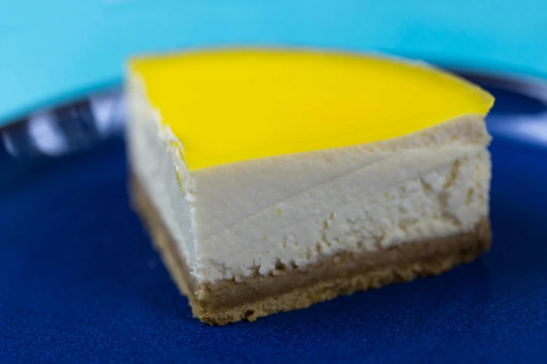 a piece of cheesecake on a blue plate, with a bright yellow aureola, square, taken with sony alpha 9, yellow carpeted