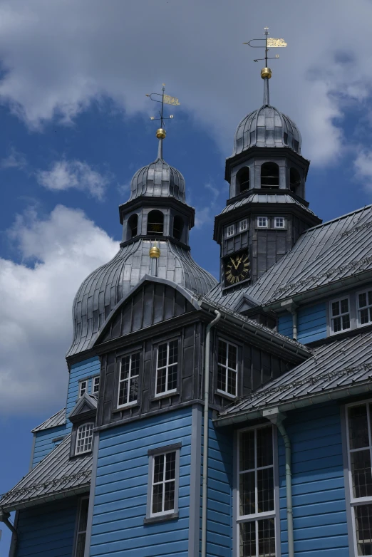 a blue building with a clock on top of it, inspired by Matthias Stom, peaked wooden roofs, domes, high elevation, two towers