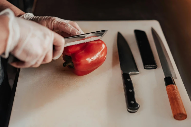 a person cutting a pepper on a cutting board, by Julia Pishtar, black steel with red trim, holding a knife, trending photo, stainless steel