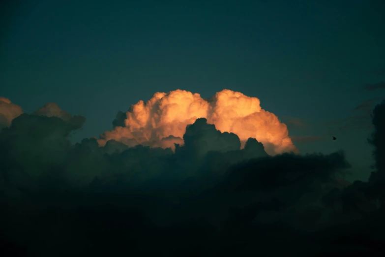 a very cloudy sky with a bird flying in the distance