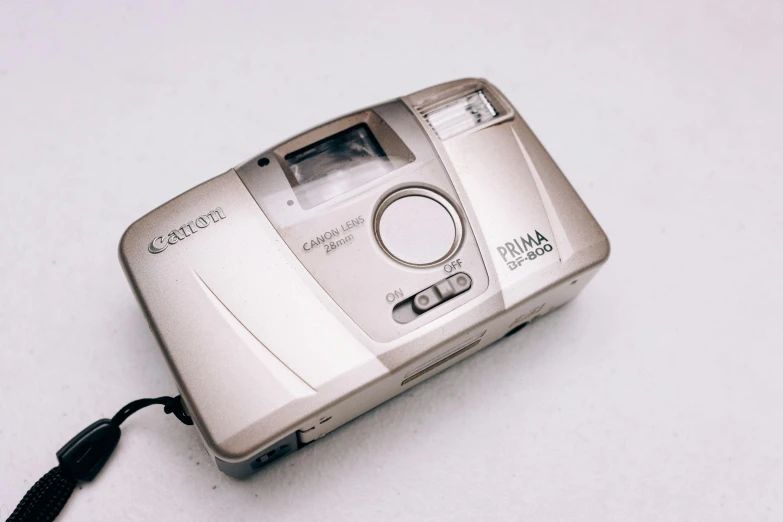 a silver camera sitting on top of a white table, 90's photo, canon photo, video game item, sigma 1.6