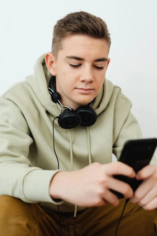 a young man sitting on the floor using a cell phone, trending on pexels, realism, portrait of 1 5 - year - old boy, lgbtq, earbuds, looking serious