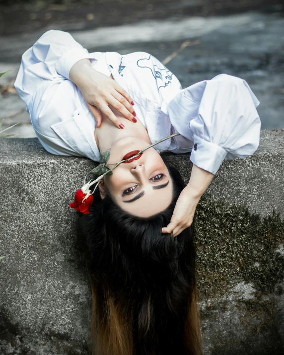 a woman laying on a concrete block holding the end of her face to the ground