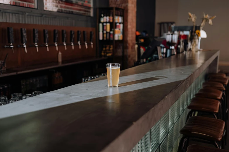 the bar has a long line of empty drinks in it