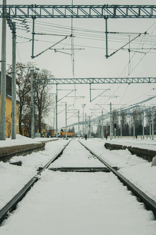 a train traveling down train tracks covered in snow, by Tobias Stimmer, pexels contest winner, electric cables, square, soviet suburbs, high quality photo