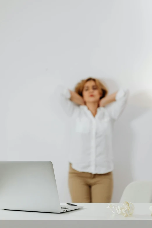 a woman standing in front of a laptop computer, trending on pexels, visual art, wearing a white button up shirt, anxiety inducing backrooms, meditative sacral pose, tinnitus