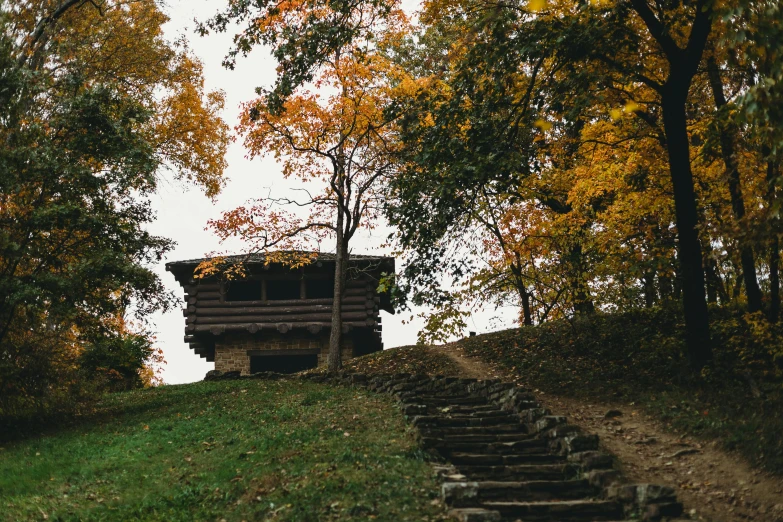 a cabin sitting on top of a lush green hillside, an album cover, unsplash contest winner, renaissance, grassy autumn park outdoor, old stone steps, autum, photo taken on fujifilm superia