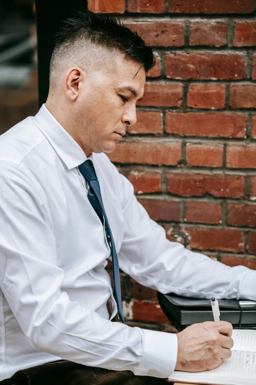 a man holding a notebook, wearing a white shirt and tie