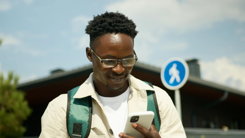 a man with a backpack looking at his cell phone, trending on pexels, happening, african facial features, avatar image, open street maps, wearing small round glasses