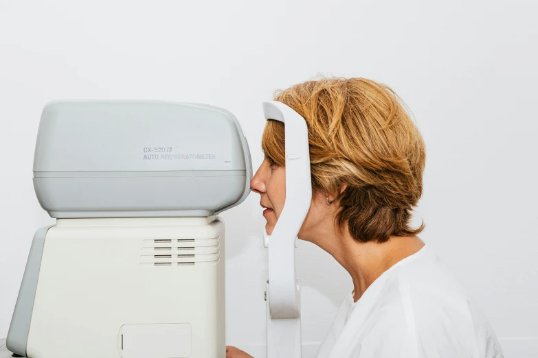 a woman getting her eye examined by a doctor, inspired by Évariste Vital Luminais, unsplash, private press, right side profile, opaque visor, white limbo, hi - res scan