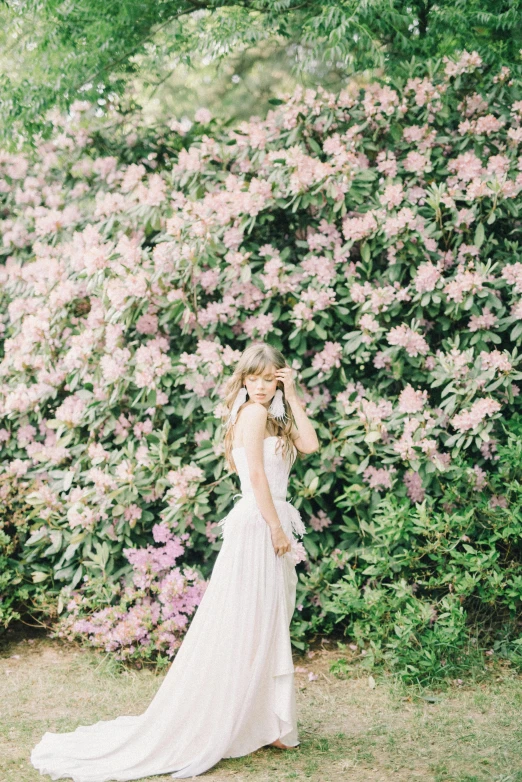 a woman in a wedding dress standing in front of a bush, unsplash, romanticism, overexposed photograph, made of flowers, photographs, may)