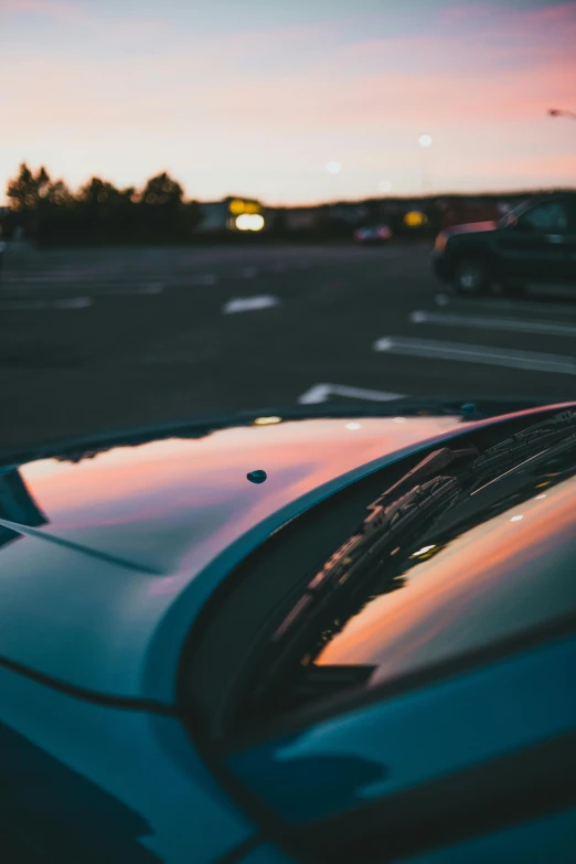 the hood of a parked car has cars in the background