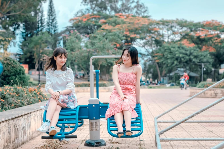 a couple of women sitting on top of a blue bench, pexels contest winner, dang my linh, swings, avatar image, sangyeob park