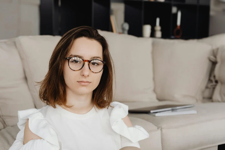 a woman wearing glasses sitting on a couch, by Julia Pishtar, trending on pexels, alexey gurylev, brown haired, avatar image